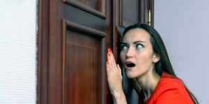 Femme écoutant à la porte