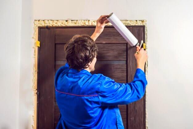 Ouvrier installant de la mousse autour de la porte