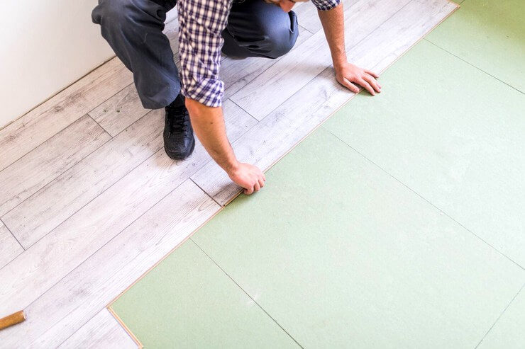 Travailleur qui pose un plancher en bois sur le sol